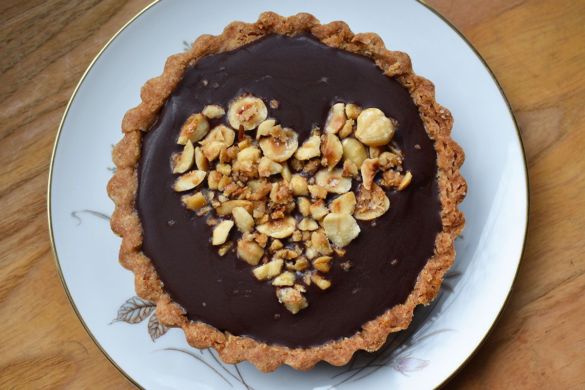 Nutella mini tart with candied hazelnuts arranged in the shape of a heart