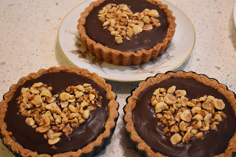 Three nutella mini tarts with candied hazelnuts arranged in the shape of a heart